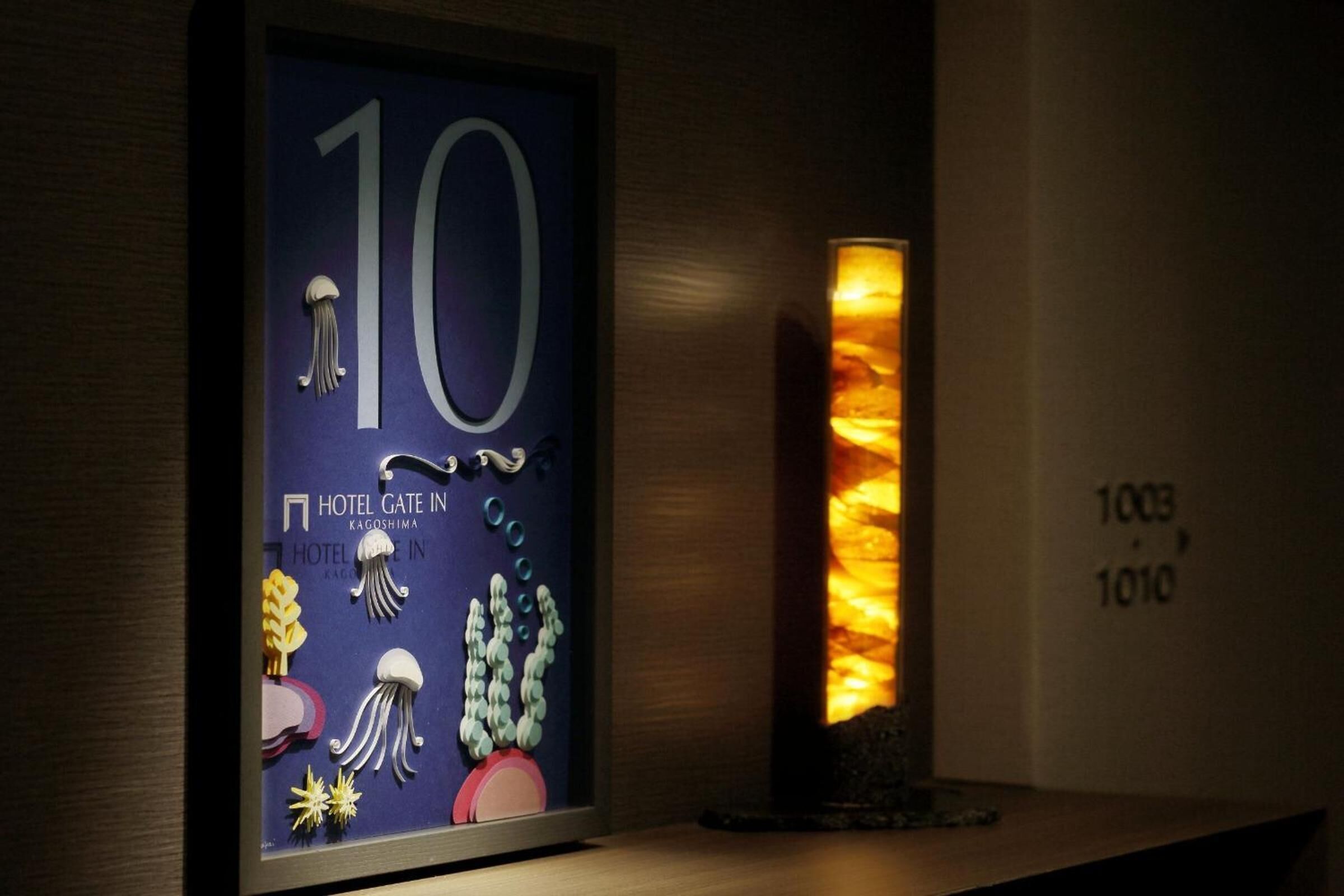 A framed number '10' with a hotel name and decorative elements, a tall pillar with a warm light, and a wall with room numbers '1003' and '1010'.