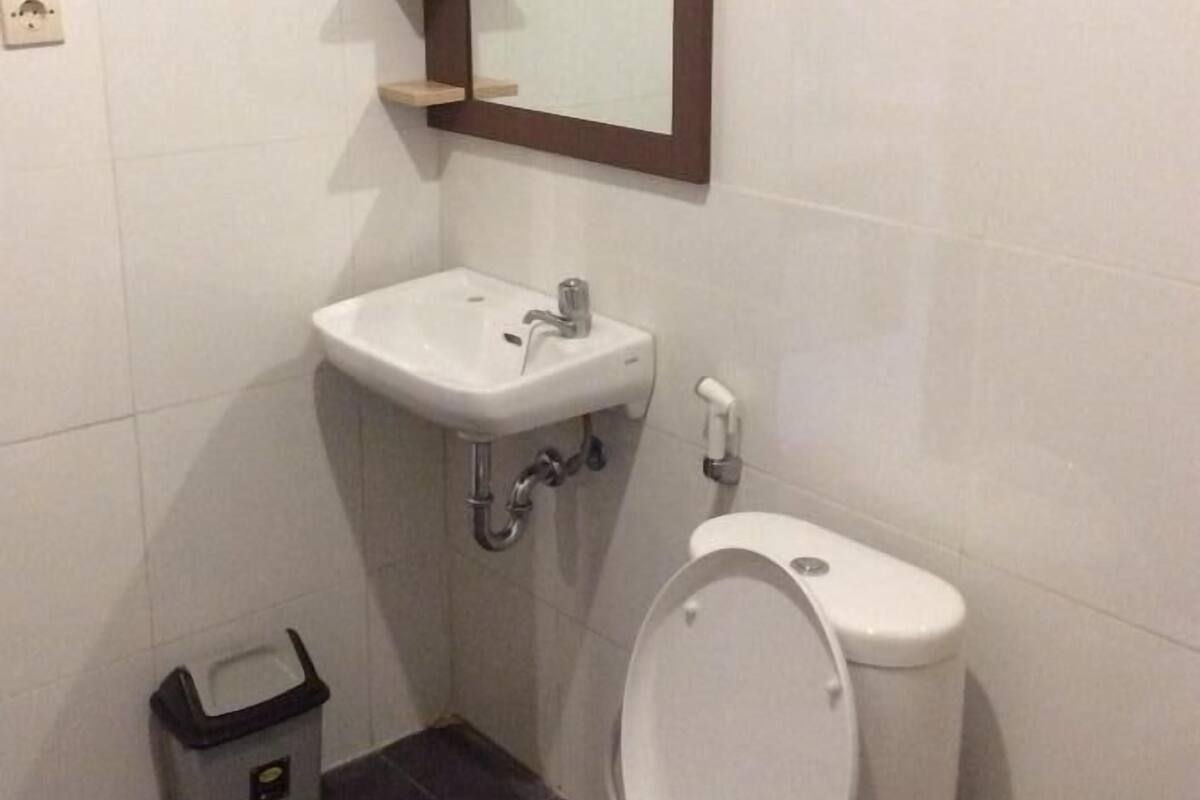 A small bathroom with a toilet, sink, and mirror.