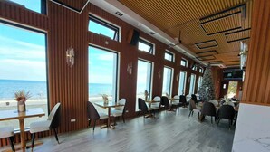 Un restaurante moderno con paneles de madera, ventanas amplias y vista al mar.