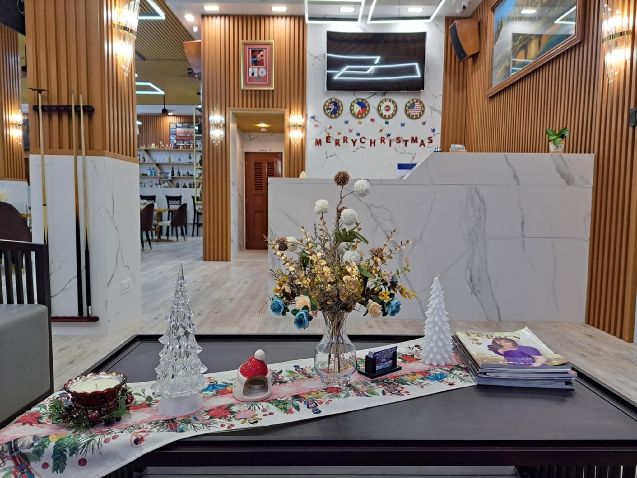 A reception area with a Christmas-themed centerpiece, including a floral arrangement, a small Christmas tree, and a candle holder.