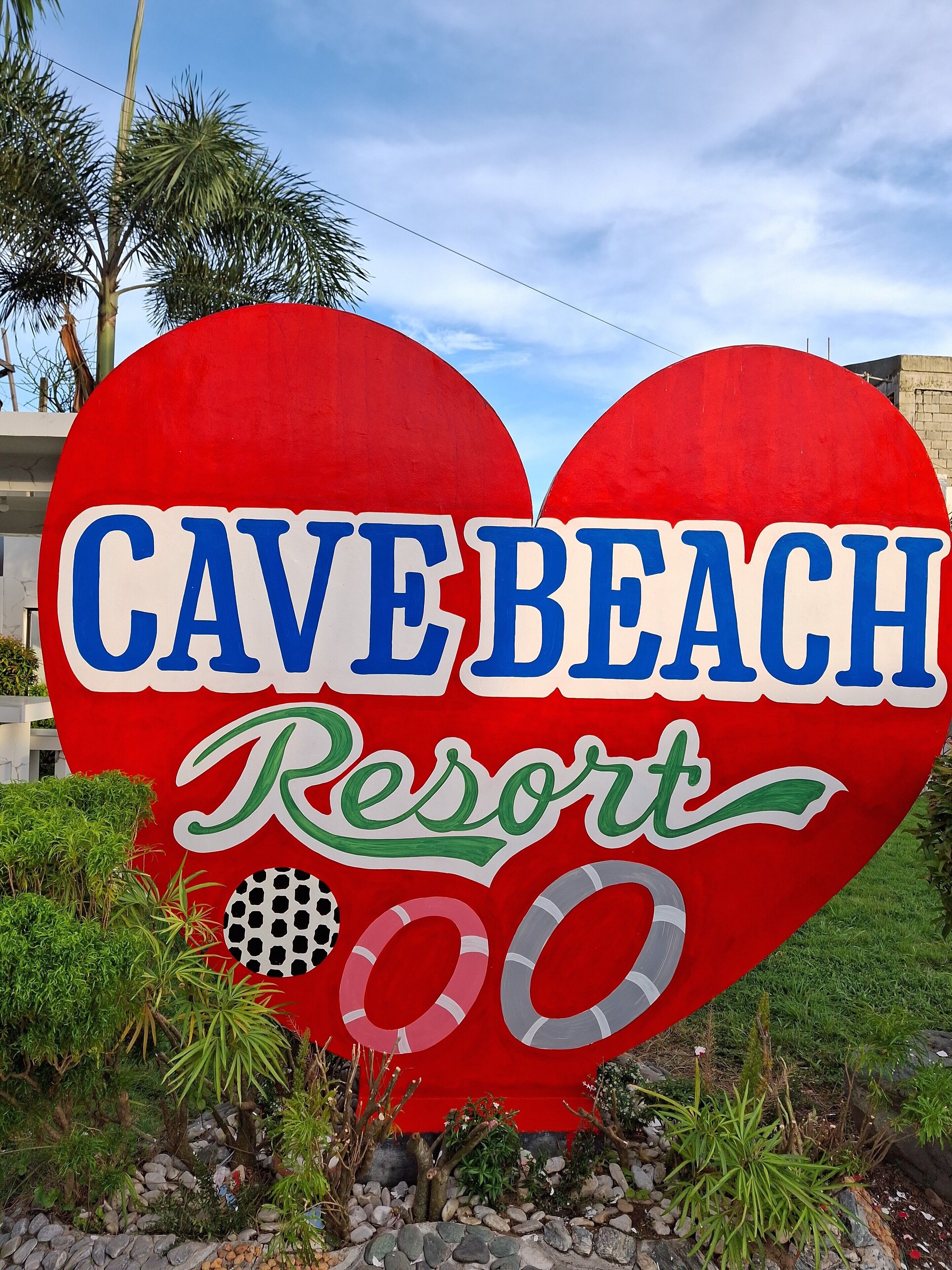 Un gran letrero con forma de corazón que muestra el texto 'CAVE BEACH Resort' y el número '00' debajo.