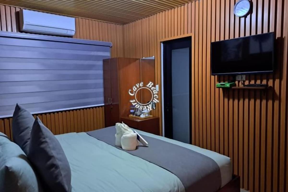A hotel room with a bed, a wardrobe, a television, and a clock on the wall.
