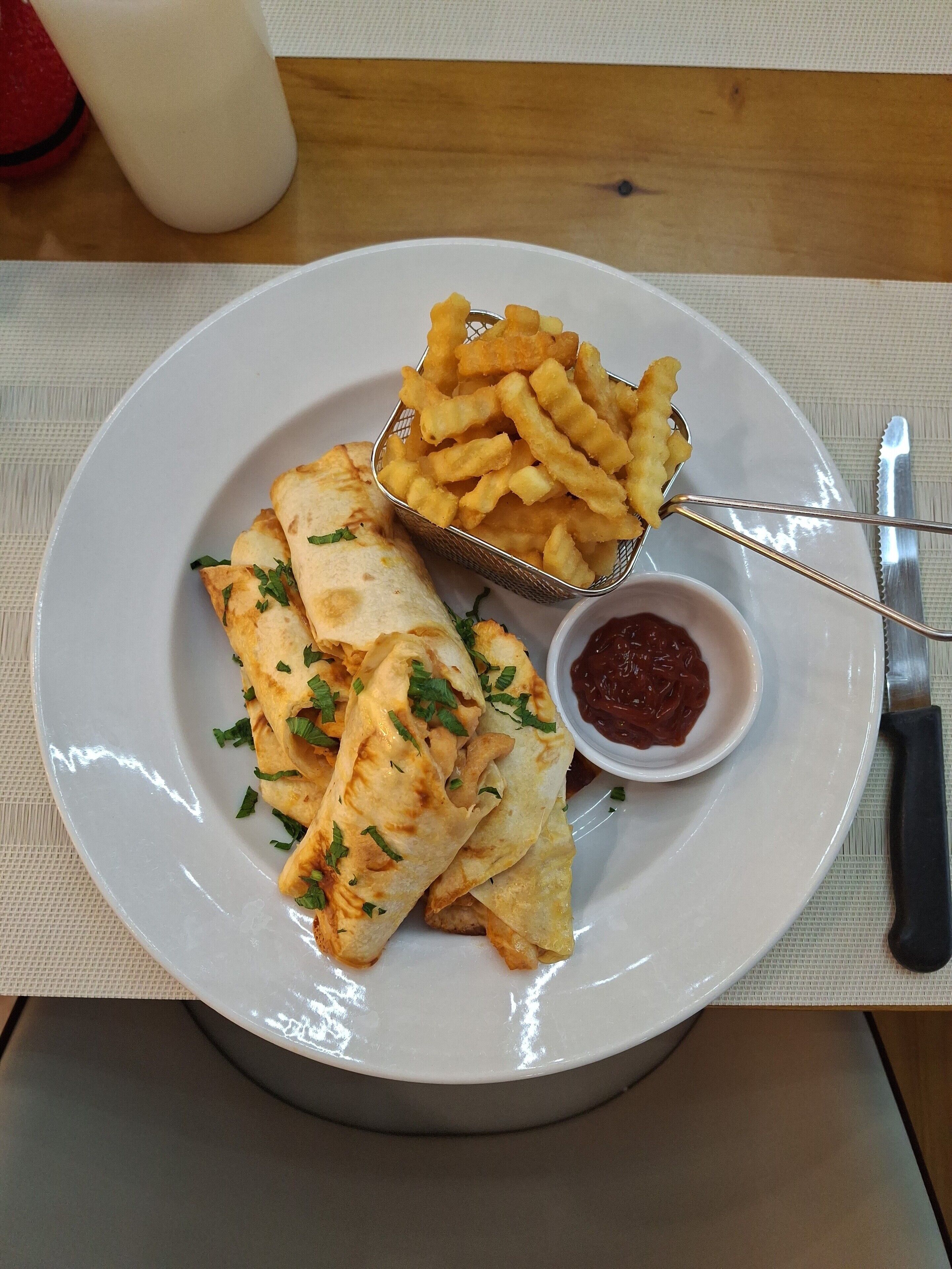 A plate with quesadillas, French fries, and a small bowl of ketchup.