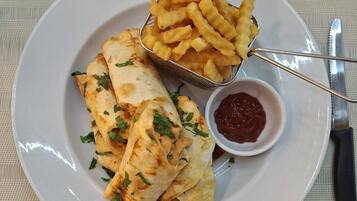 A plate with quesadillas, French fries, and a small bowl of ketchup.