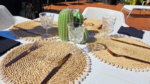 Un espace de restauration en plein air agrémenté de sets de table en fibres tressées, de couverts et de verres.