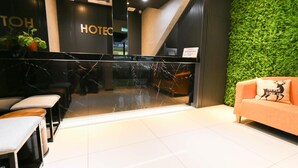 A hotel reception area with a marble counter, seating, and a green wall.