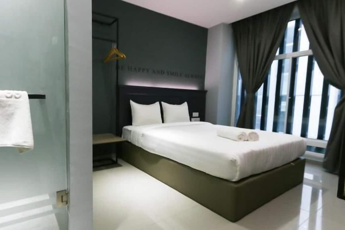 A modern bedroom with a large bed, a bedside table, a hanging light, and a view of the outside through a window.