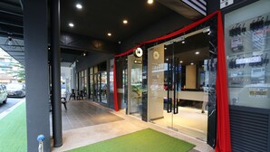 A modern building entrance with glass doors, a red curtain, and a green artificial turf area.