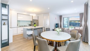 Une cuisine moderne avec des meubles blancs, un îlot central et un coin repas comprenant une table ronde et des chaises.