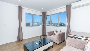 Un salon moderne avec un canapé, une table basse et de grandes fenêtres donnant sur la ville.