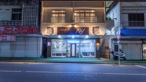 Un immeuble de deux étages dont le rez-de-chaussée abrite un bar appelé « BAR BER’S NY ».