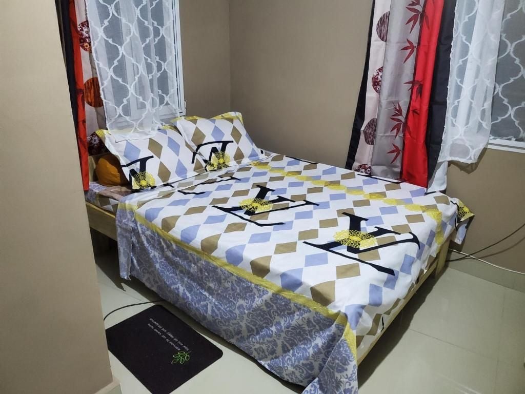 A single bed with a patterned bedspread, a bedside table, and curtains with a floral pattern.