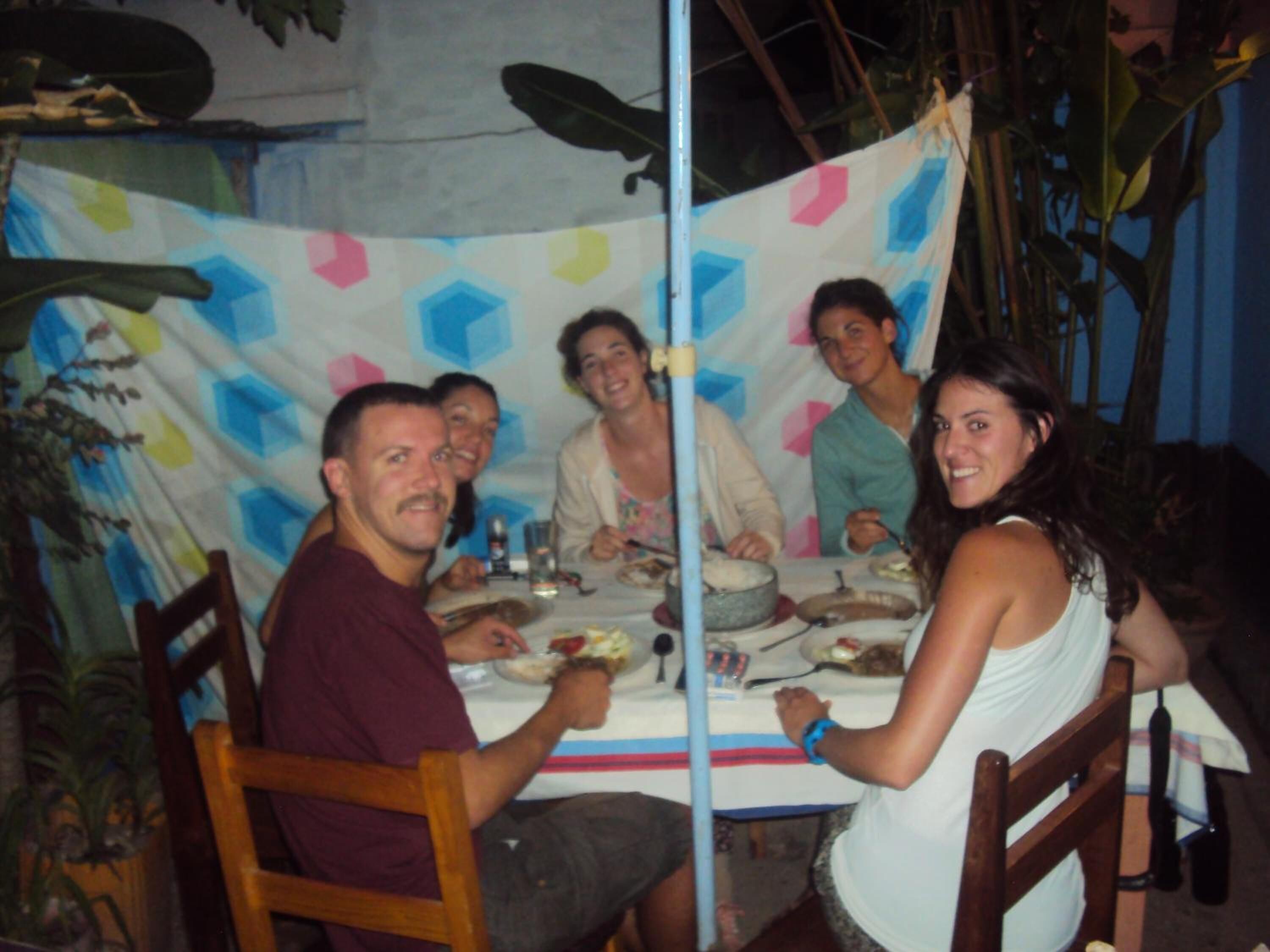 A group of people dining at a table with a colorful geometric tablecloth.