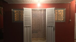 A room with a red wall, a zebra-patterned curtain, and a white door with shutters.