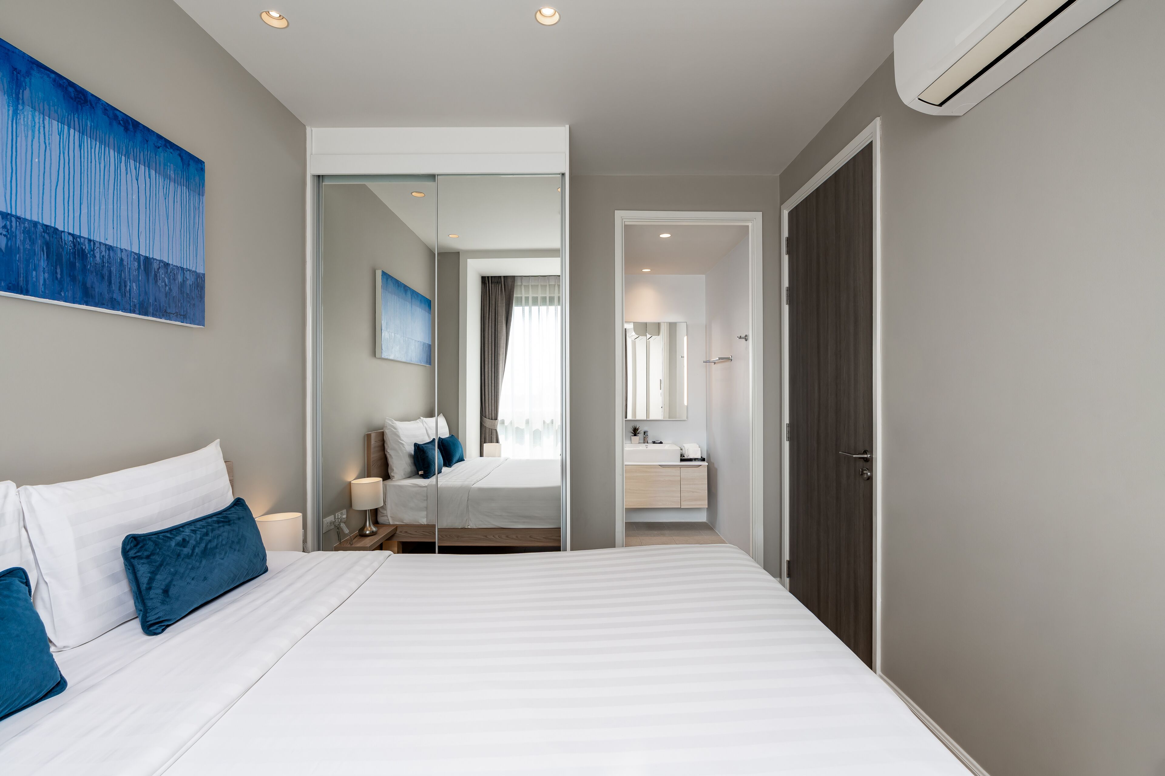 Ein modernes Hotelzimmer mit einem großen Bett, einem Badezimmer mit Spiegel und Blick in einen anderen Raum.