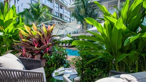 A poolside area with lounge chairs, a table with a magazine, and lush greenery. - Diamond Resort Phuket Official Account (Choeng Thale)