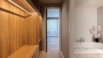 A modern bathroom with a wooden bench, a bathtub, and a view of a balcony.