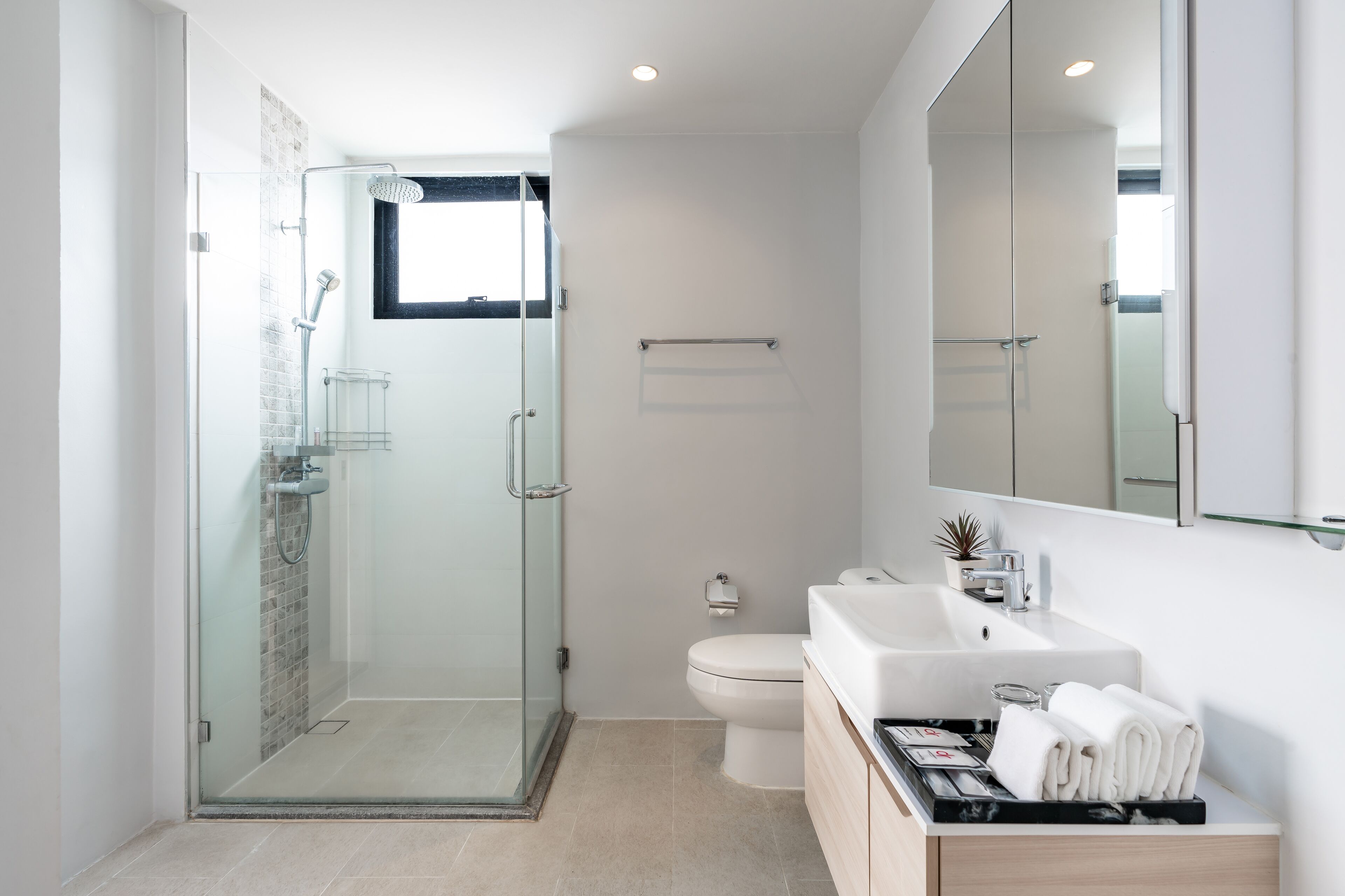 Een moderne badkamer met een douchecabine van glas, een wit toilet en een wastafel met een wastafel en spiegel.