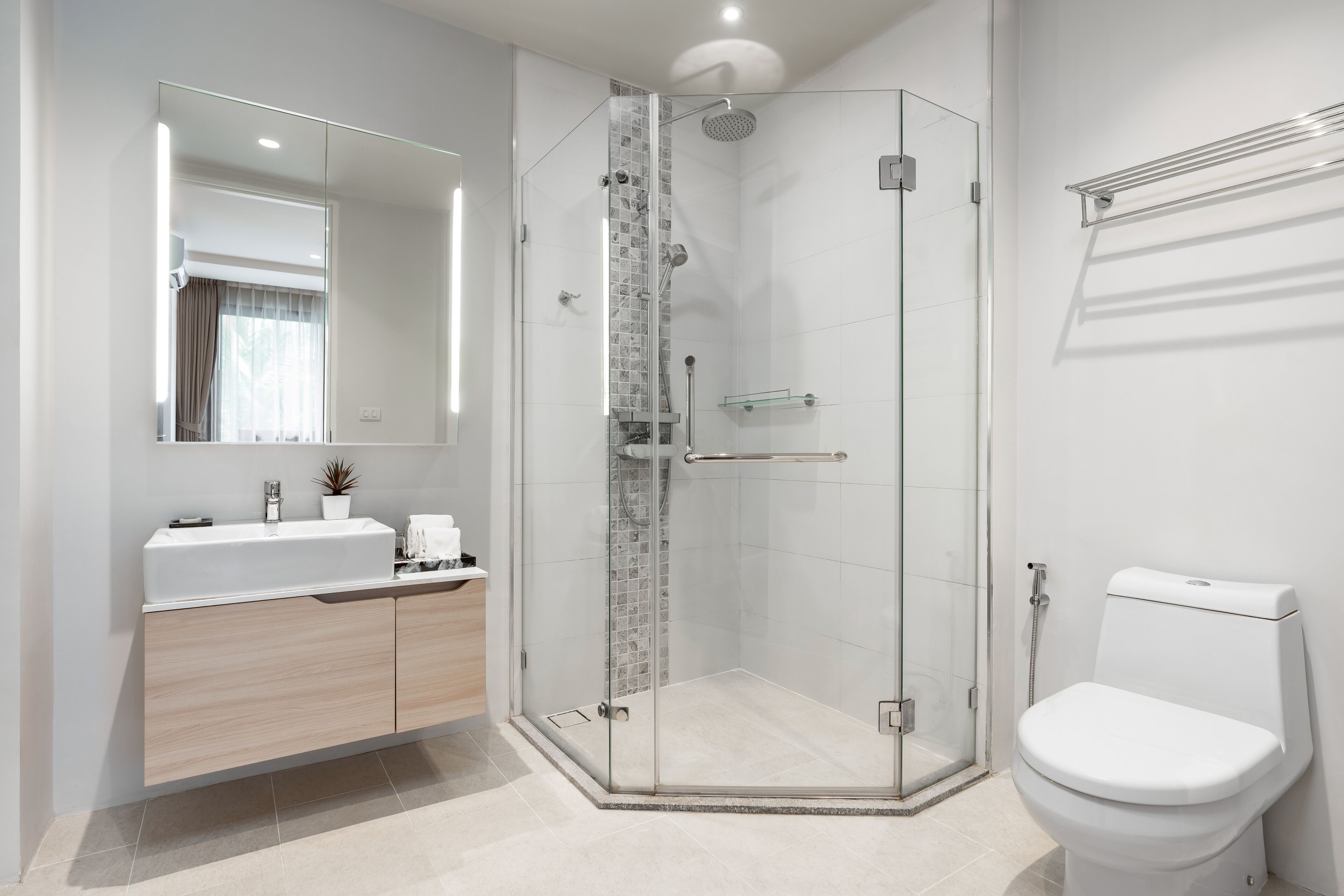 Un baño moderno con ducha de vidrio, lavamanos blanco y retrete.