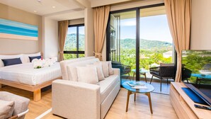 A modern hotel room with a bed, sofa, balcony, and a TV. - Diamond Resort Phuket Official Account (Choeng Thale)