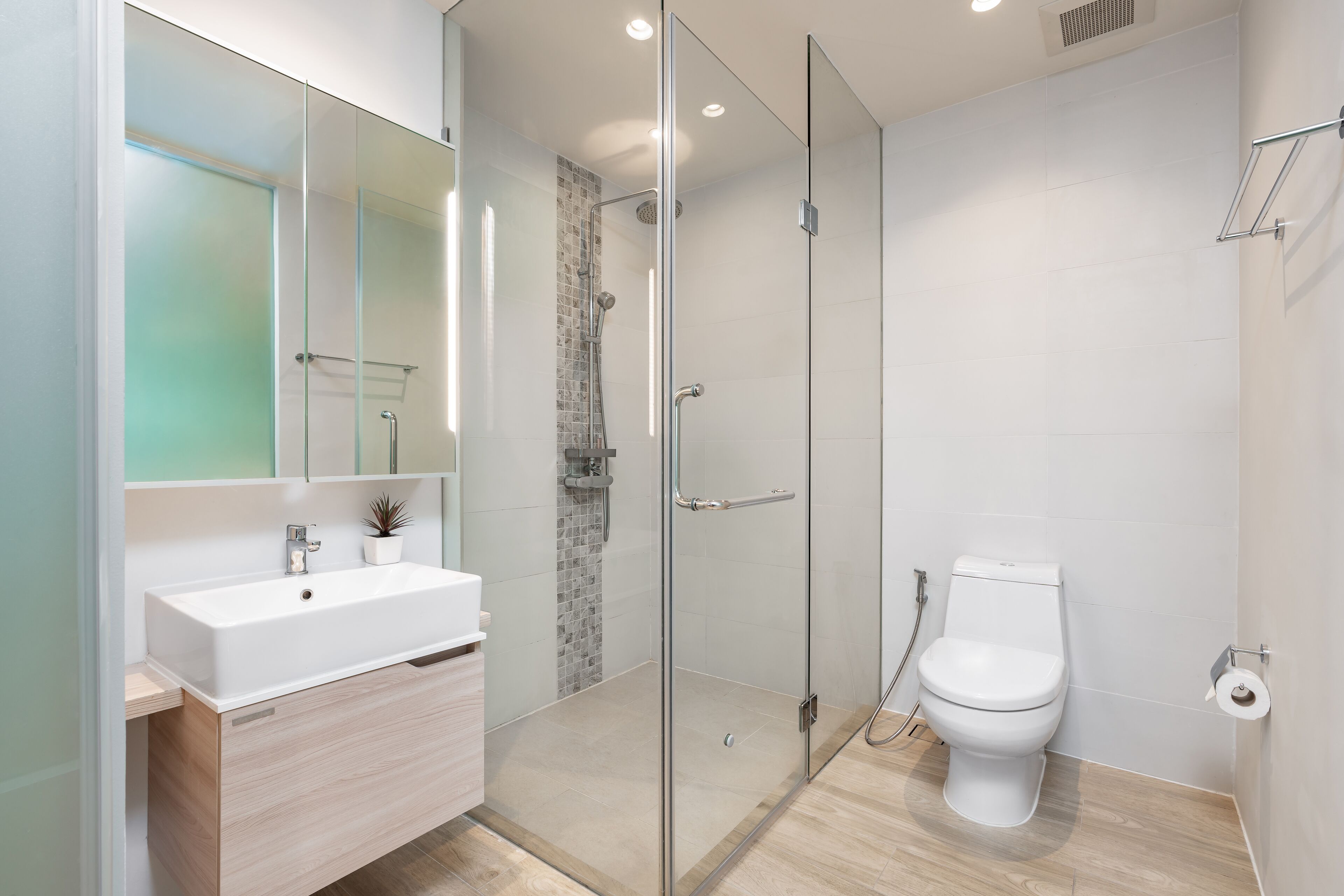 A modern bathroom with a glass-enclosed shower, a white sink, and a toilet.
