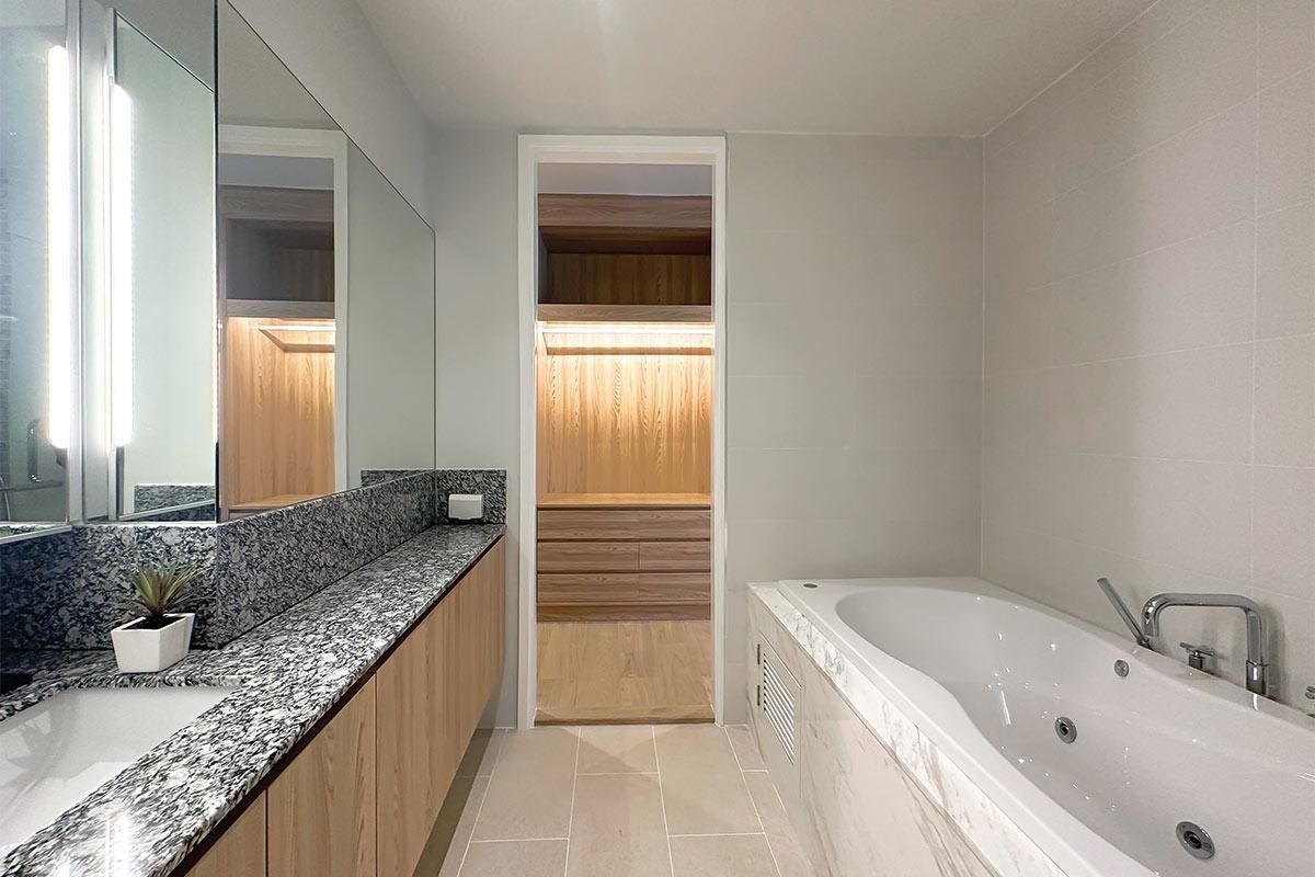 Une salle de bain moderne avec une grande baignoire, un plan de travail agrémenté d’une plante et un meuble-lavabo en bois.