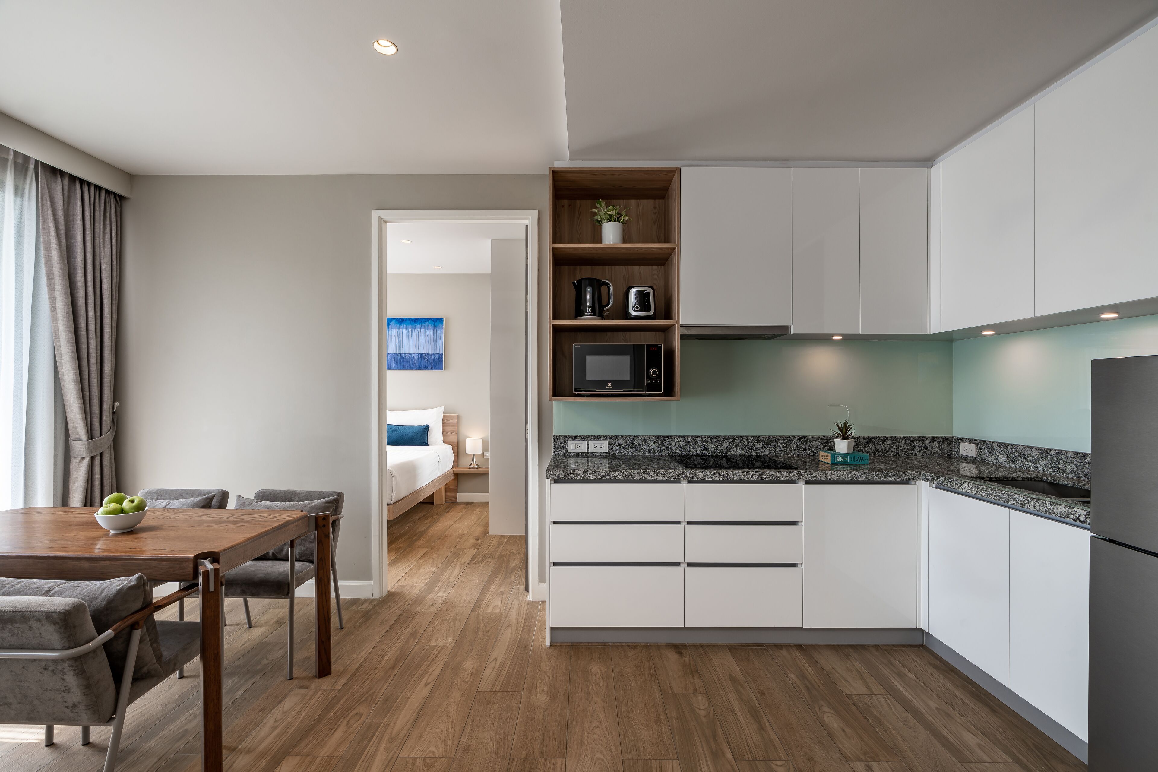 A modern kitchen with white cabinets, a granite countertop, and a built-in microwave.