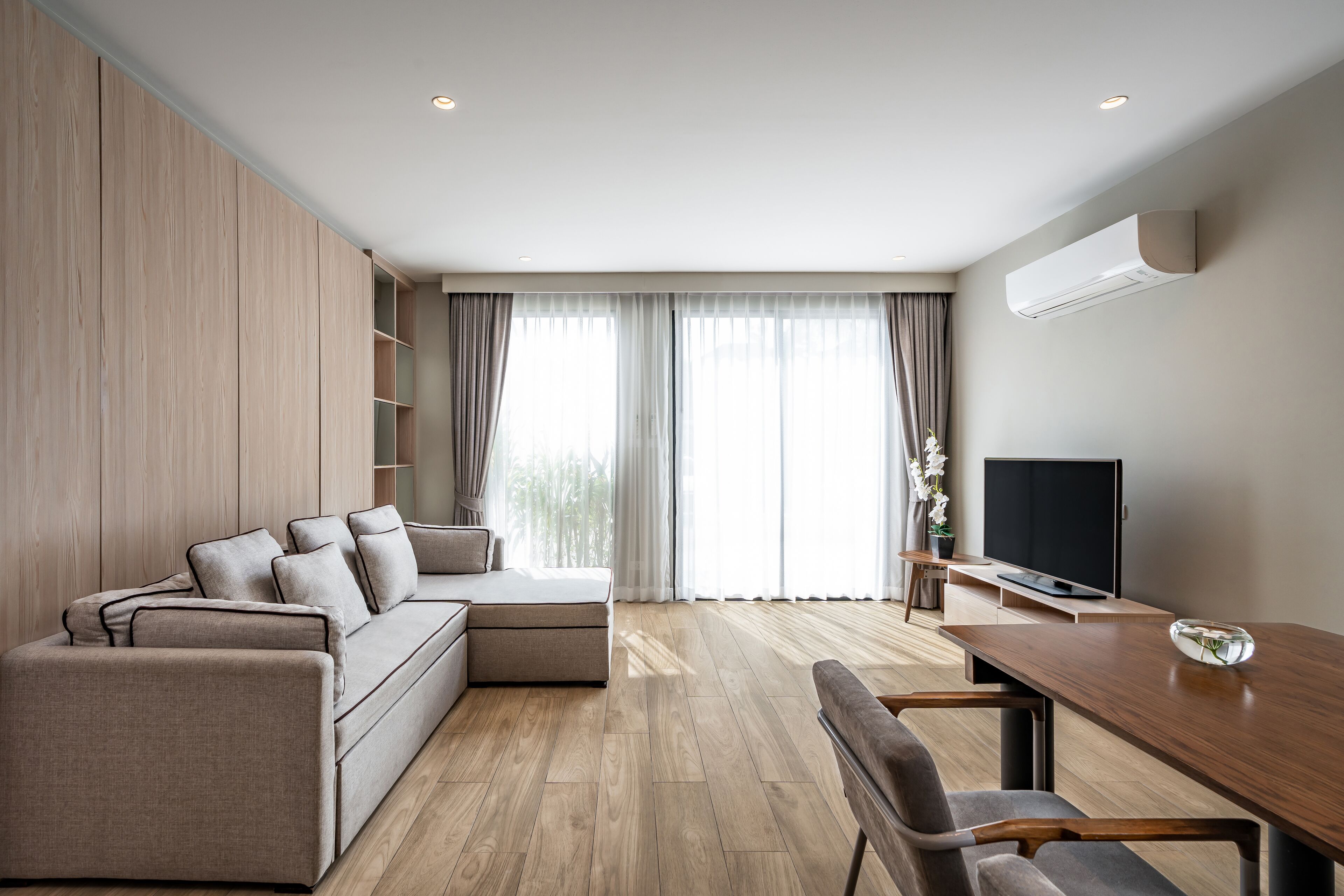 A modern living room with a sofa, a dining table, and a TV.