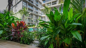 A modern hotel with multiple balconies, a swimming pool, and lush tropical vegetation. - Diamond Resort Phuket Official Account (Choeng Thale)