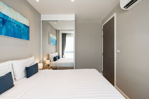 Una habitación de hotel moderna con una cama grande, mesitas de noche, un espejo y obras de arte en las paredes.