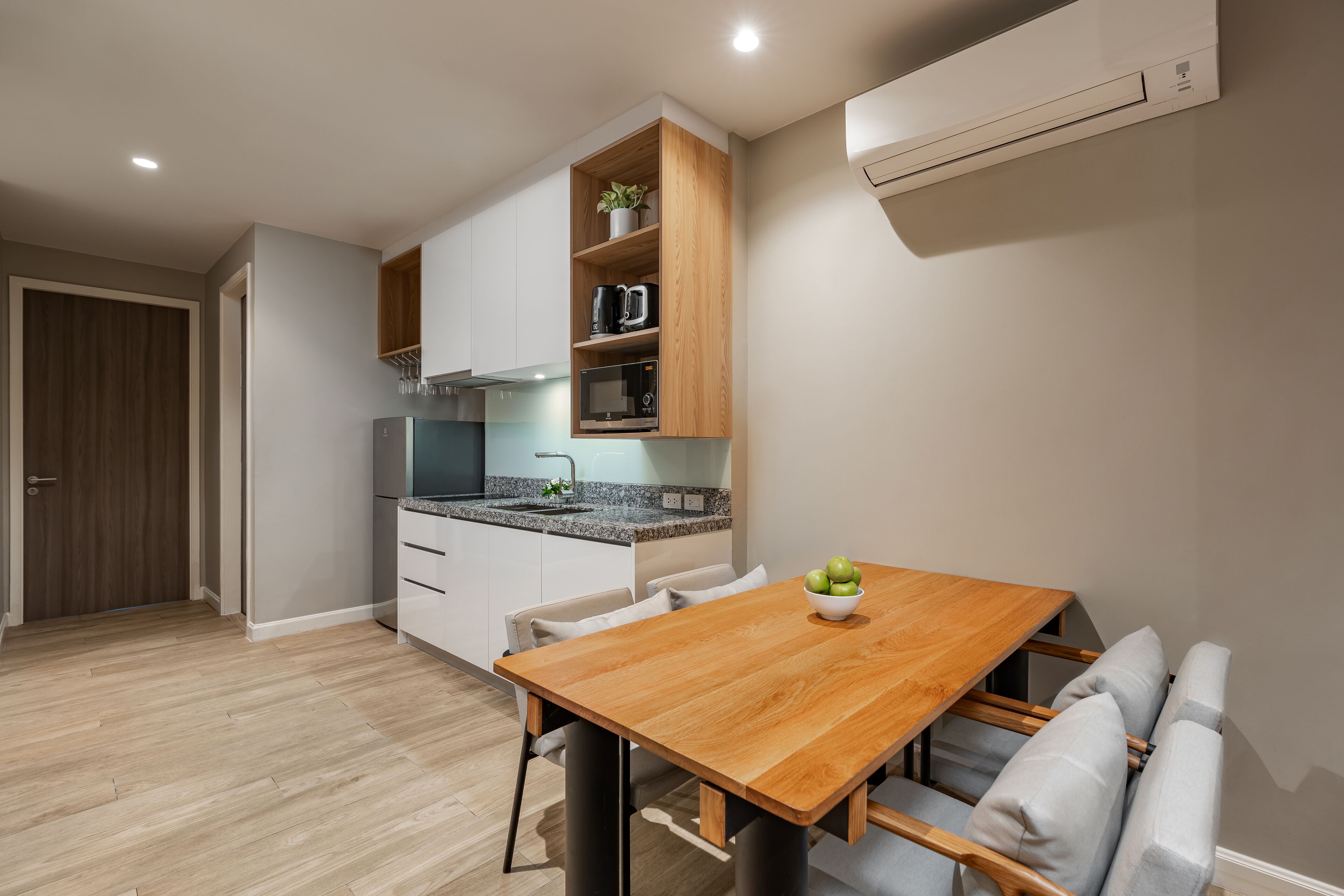 Een moderne keuken met inbouwapparatuur, een houten eettafel en een zithoek.