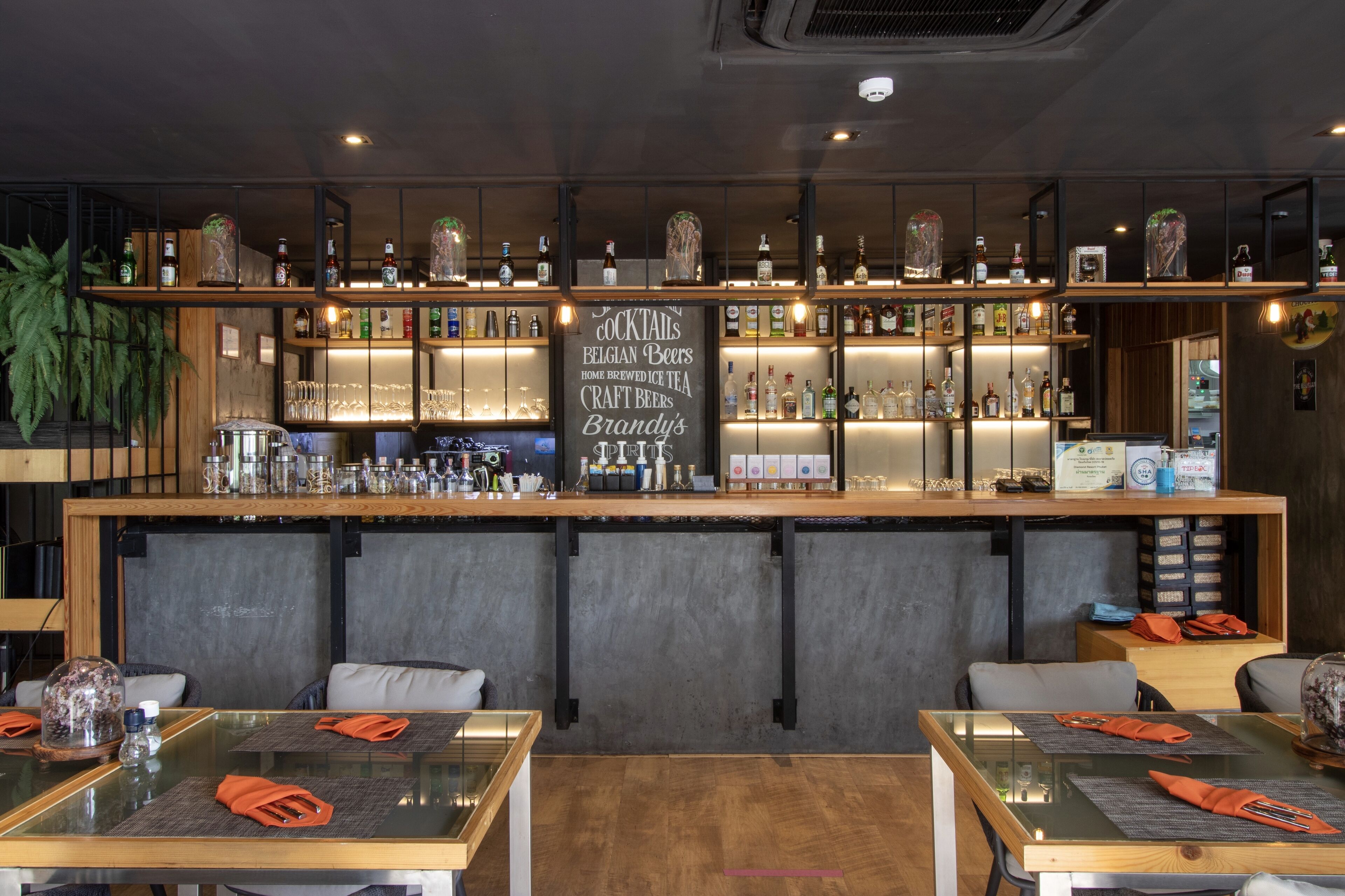 A bar area with shelves of bottles and glasses, a chalkboard menu, and seating with tables and chairs.