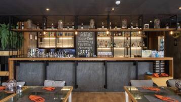 A bar area with shelves of bottles and glasses, a chalkboard menu, and seating with tables and chairs.
