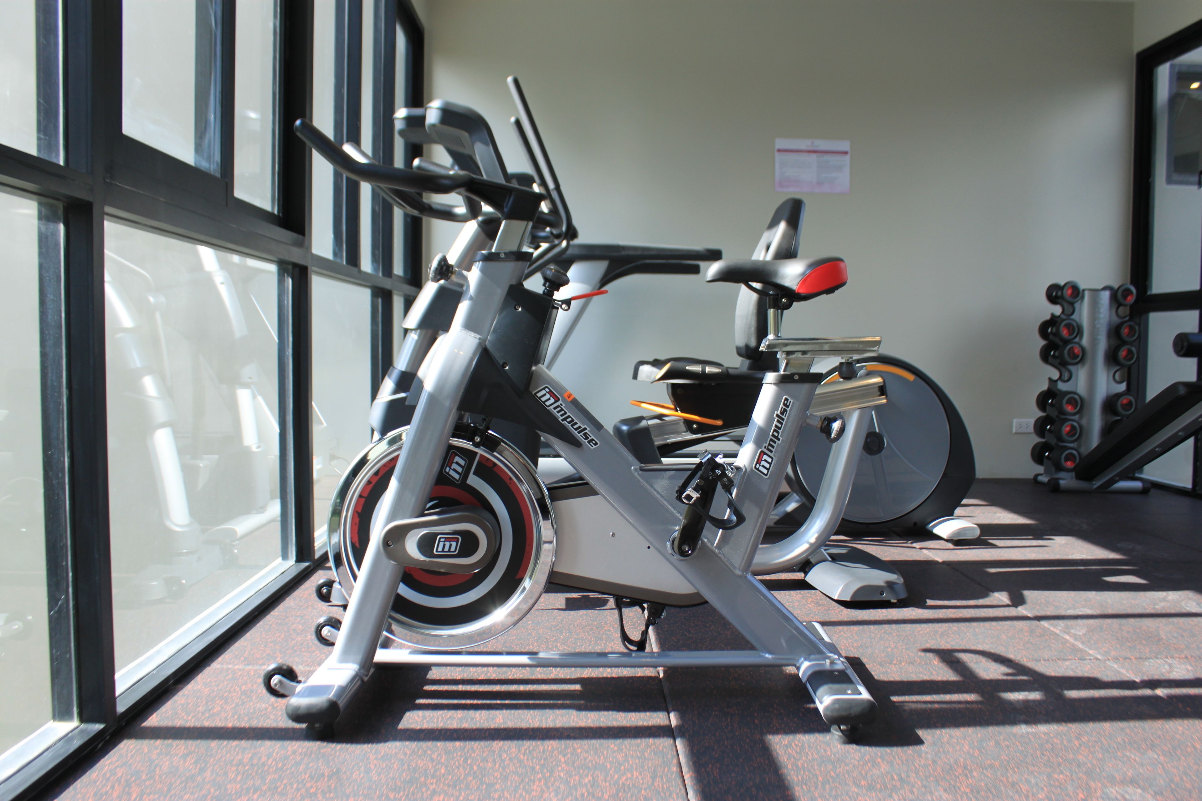 Una bicicleta estática en un gimnasio con una ventana y un papel pegado a la pared.
