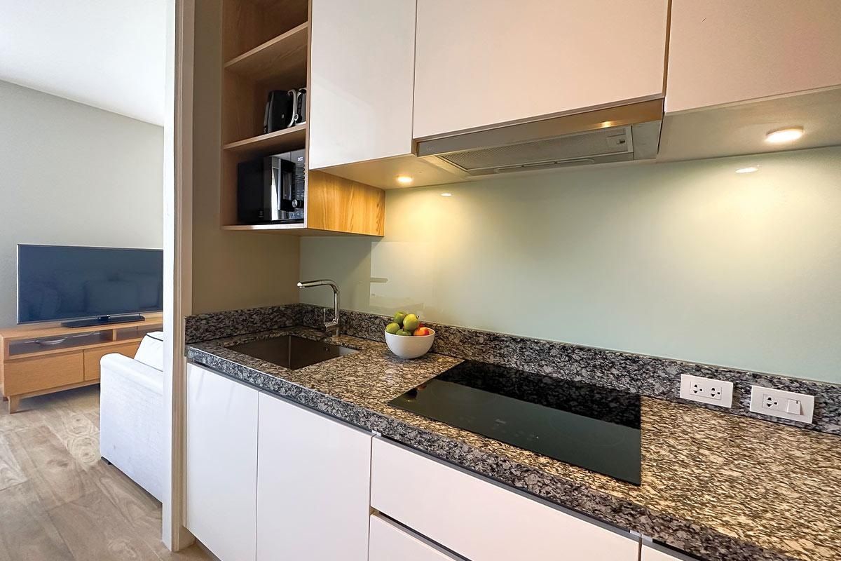 Una cucina moderna con piano di lavoro in granito, forno integrato e una ciotola di frutta.
