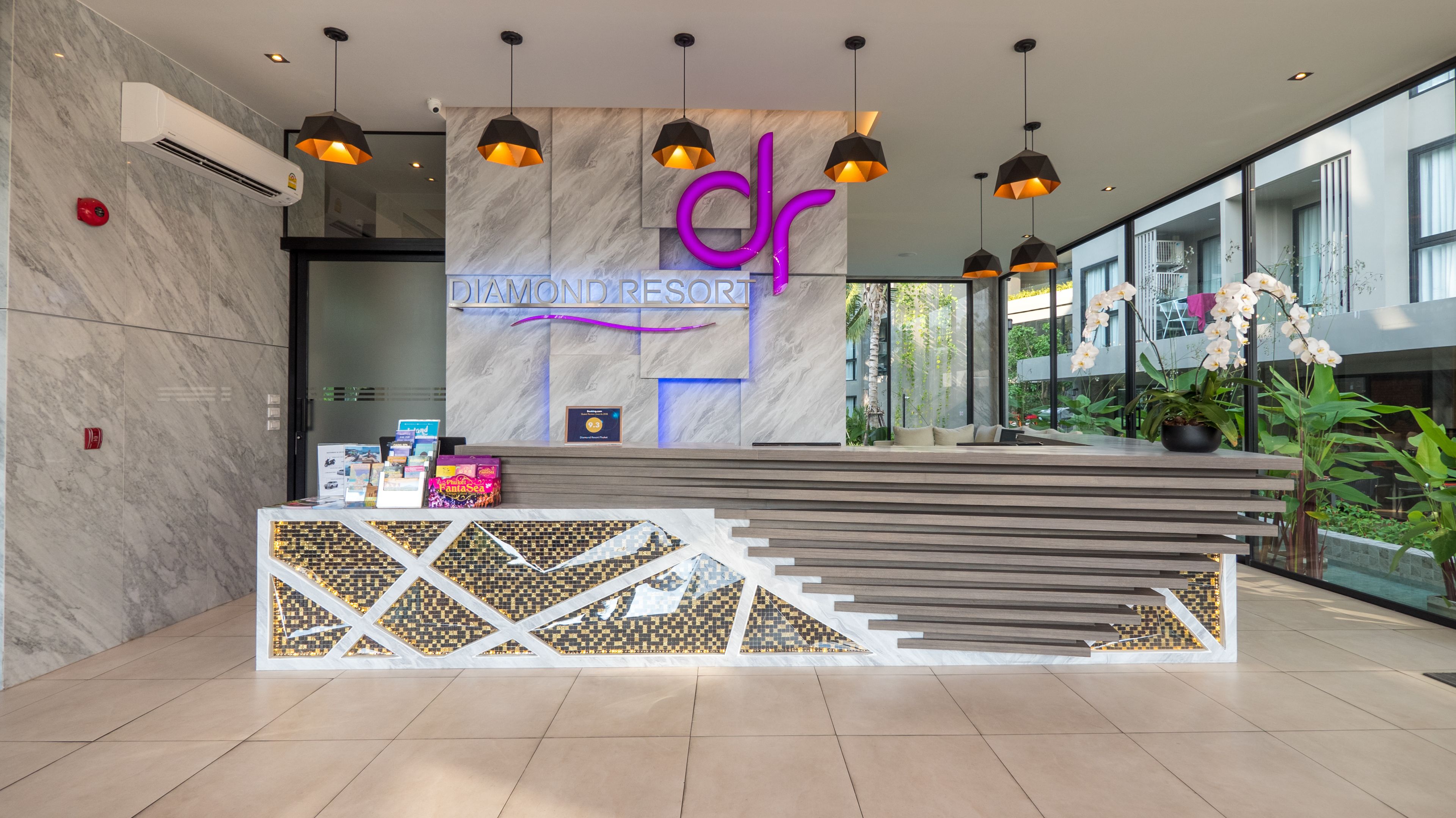 A modern reception desk with a marble wall, a sign reading "Diamond Resort," and a staircase leading to an upper level.