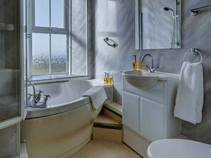 A bathroom with a bathtub, a sink, and a toilet. There is a window providing natural light. - Bosavern House (Penzance)