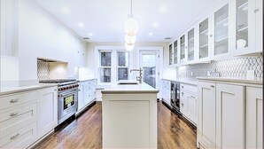 A modern kitchen with white cabinetry, a central island, and a hanging light fixture.