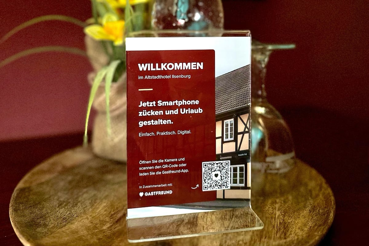 A welcome sign at the Altstadthotel Ilsenburg with a QR code and a smartphone instruction.