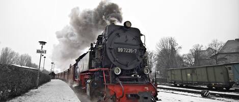 Uma locomotiva a vapor com o número 99 7235-7 em uma linha férrea coberta de neve.
