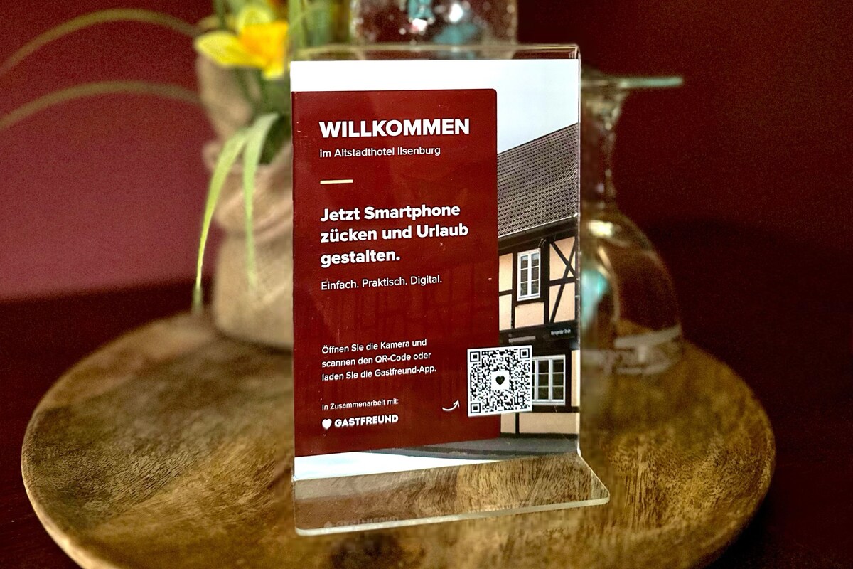 A welcome sign at the Altstadthotel Ilsenburg with a QR code and a smartphone instruction.