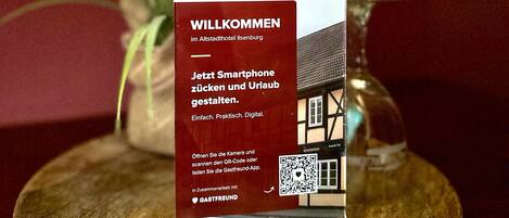 Placa de boas-vindas no Hotel Altstadthotel Ilsenburg com um código QR e instruções para smartphone.