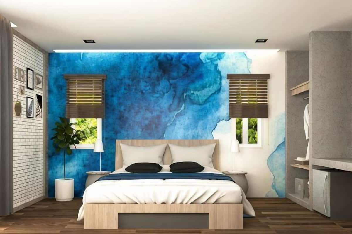 A modern bedroom with a large bed, two bedside tables, a wall mural, and a potted plant.
