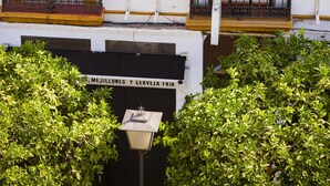 A building with a sign reading "PENSION-ROOMS" and another sign below stating "MEJILLONES Y CERVEZA FRIA". - Pensión dulces sueños (Seville)