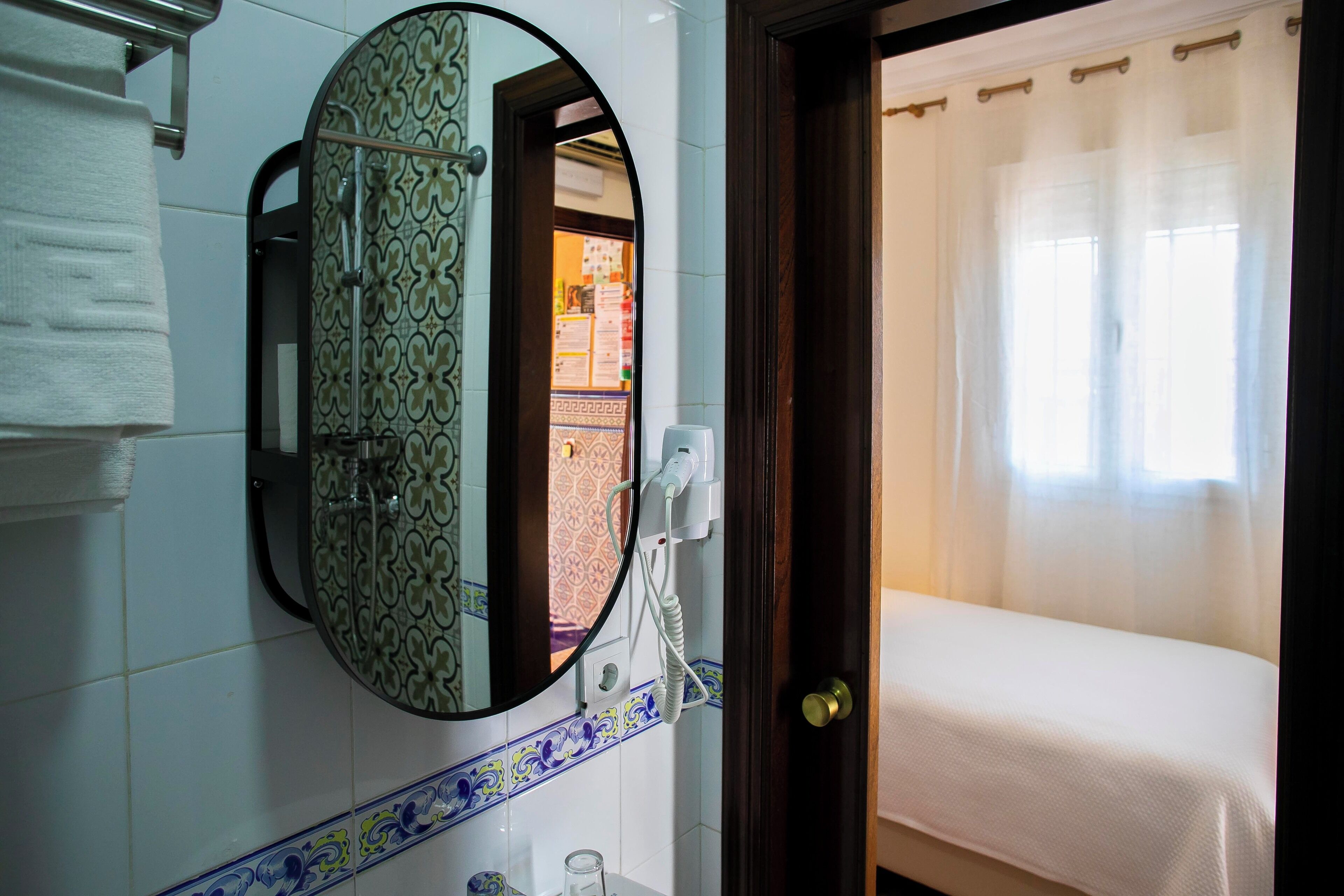 A bathroom with a round mirror, a towel rack, a sink, and a shower area.
