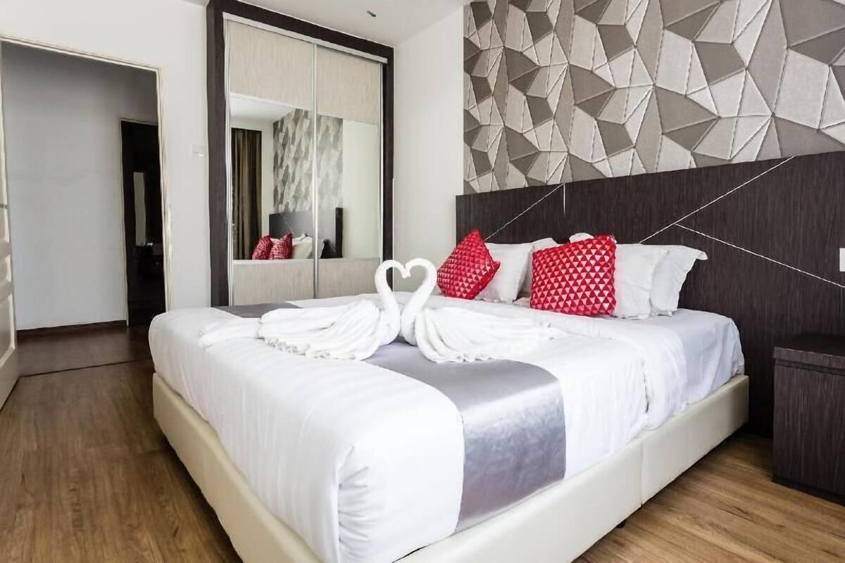 Habitación de hotel con una cama grande, un espejo, un diseño geométrico en la pared y un armario.