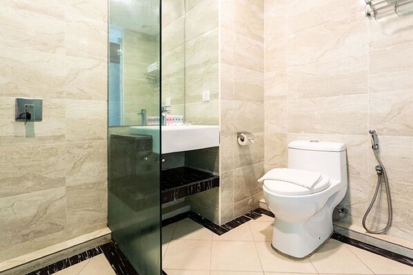 Une salle de bain moderne avec une douche à parois de verre, des toilettes blanches et un lavabo doté d’un plan de travail en marbre.