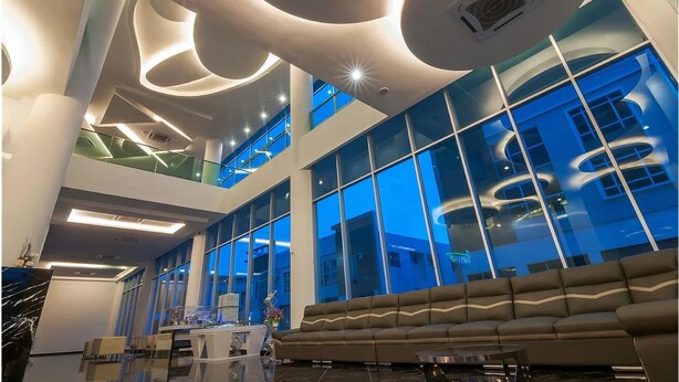 Een moderne lobby met een hoge plafond, grote ramen en een centrale zithoek.