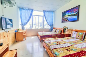 A hotel room with two beds, a desk, a chair, a TV, and a painting on the wall. - Hoang Nguyen Hotel (Lam Vien - Da Lat)