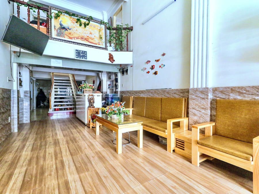 Un hall con suelo de madera, un sofá, una mesa y un televisor en la pared.